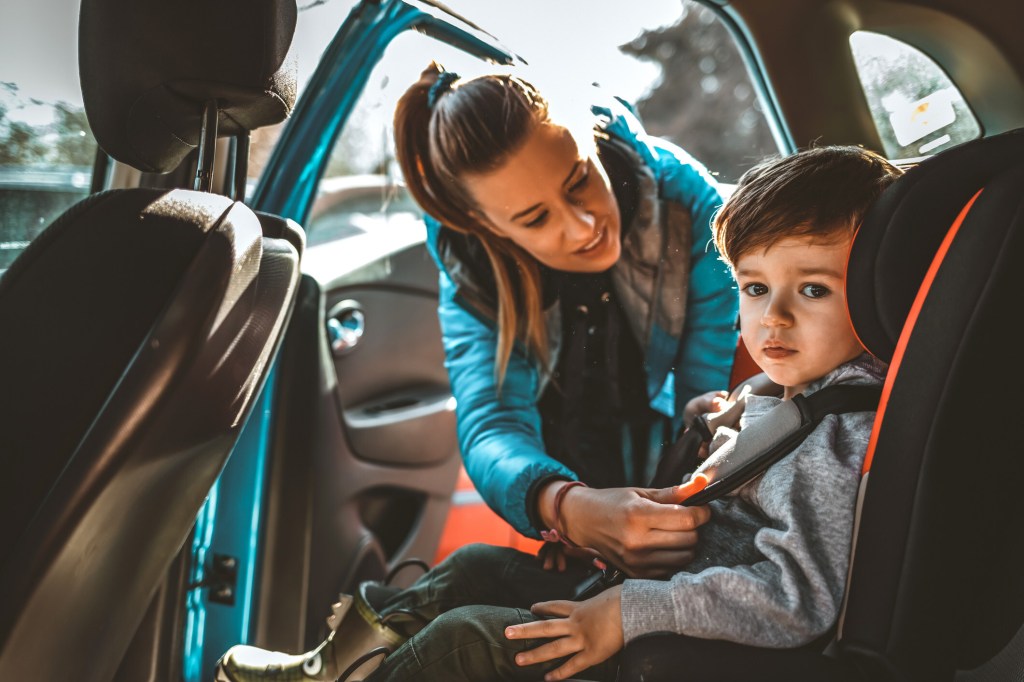 Mother buckling her child in a car seat