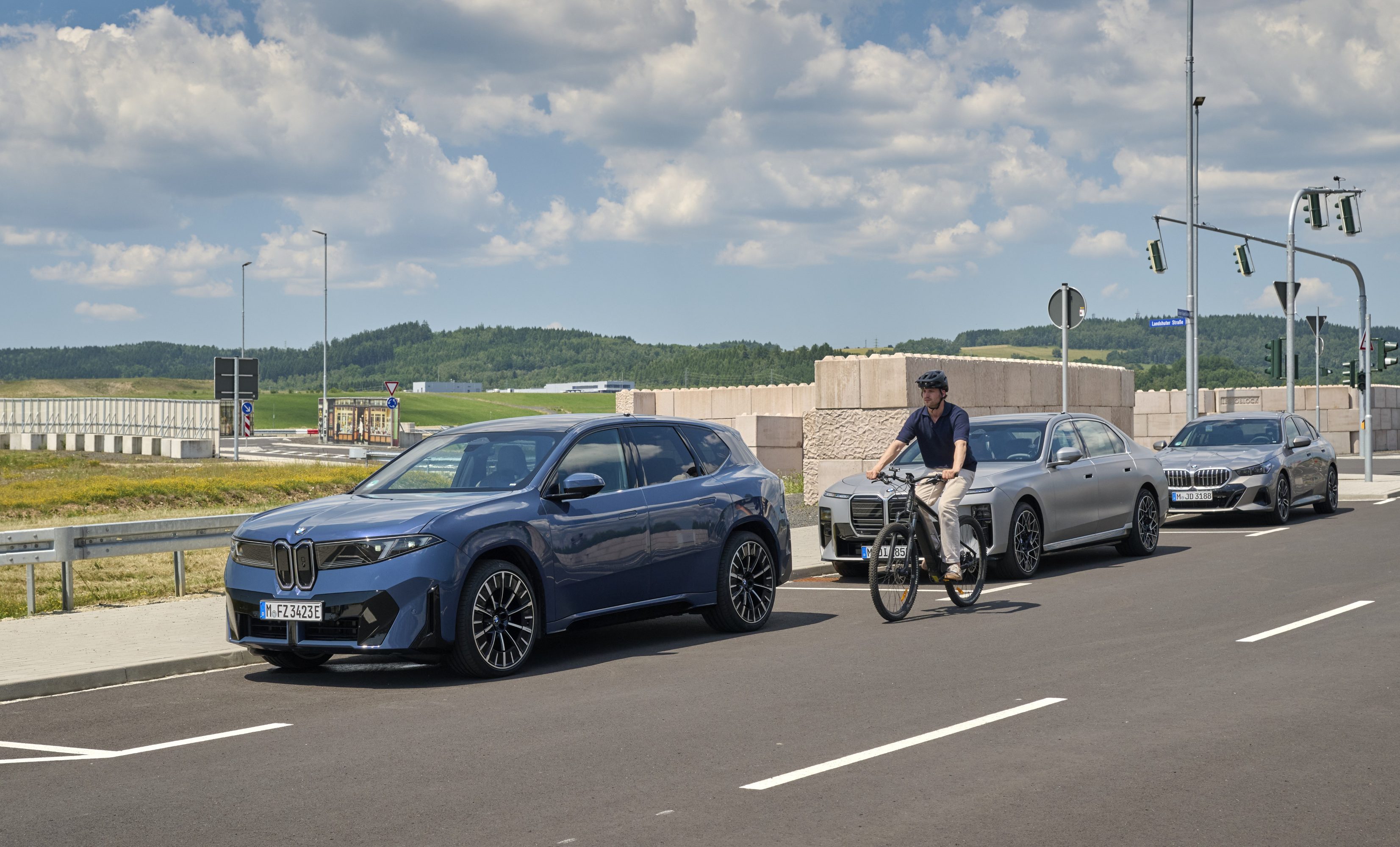 Cyclist riding past parked BMWs