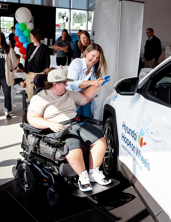 Patient placing handprint on Hyundai Hope on Wheels vehicle