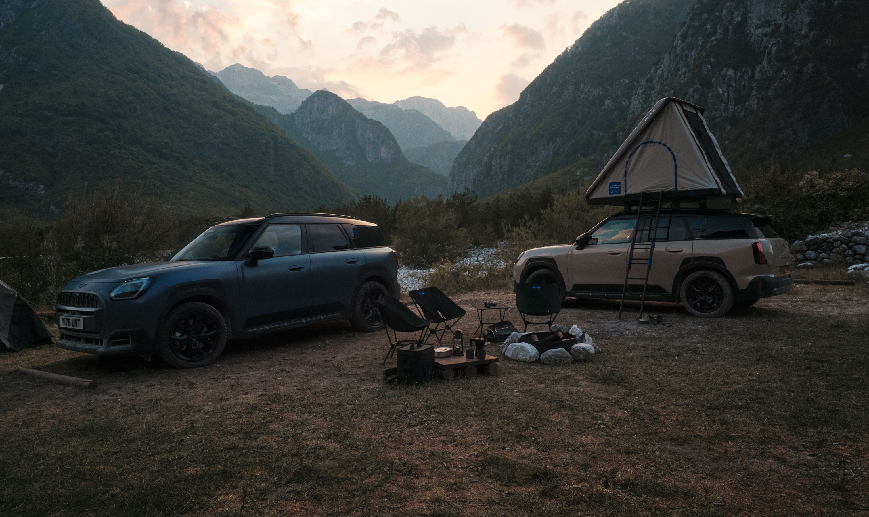 Mini Countryman Untamed Edition at campground with roof tent open and camping chairs in front of fire pit